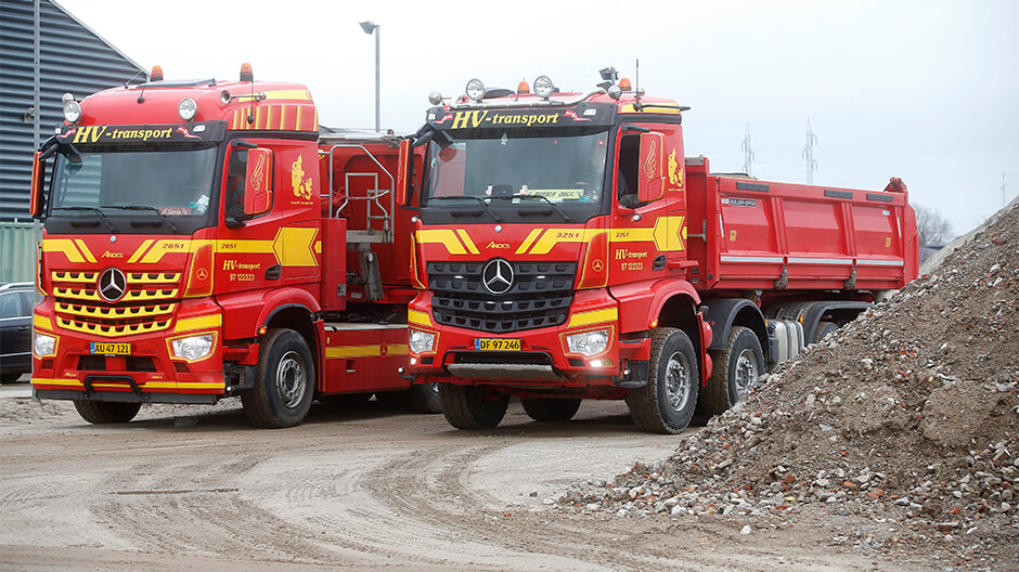 To lastbiler fra HV-transport ved siden af hinanden.